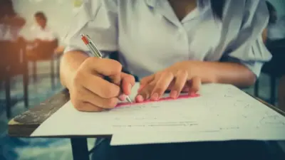 пишущая экзамен ученица за партой
